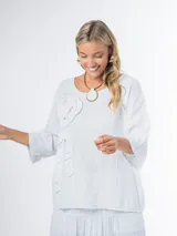 Remera oversized confeccionada en lino italiano color blanco, con aplique tridimensional de flor en el mismo lino.