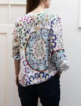 Blusa estampada marca Grand & Greene, con cuello a la base y escote en V. Tiene mangas 3/4 con puños elásticos fruncidos.