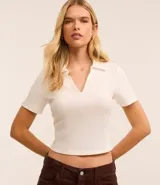 Blusa color blanco con cuello polo y escote en V, de manga corta y corte ajustado.
