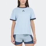 Remera deportiva Le Coq Sportif, color celeste claro, con cuello redondo y ribetes en contraste azul marino en cuello y mangas. Presenta el logo del gallo bordado en el pecho.