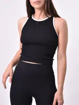 Musculosa negra de punto acanalado con cuello redondo y ribete blanco en cuello y sisas.