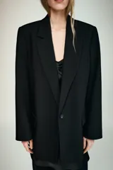 Blazer negro de manga larga con cuello solapa y cierre frontal de un solo botón. Presenta bolsillos delanteros con solapas.