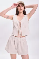 Top sin mangas color crudo con rayas verticales finas en color beige, escote en V con lazos ajustables y corte crop.