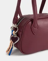 Cartera bowling color gris claro de cuerina con doble asa corta de mano, correa regulable y cierre superior.