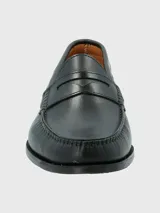 Zapato mocasín de cuero color marrón, con detalle de antifaz y suela de cuero y goma.