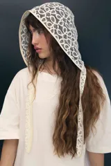 Capucha de encaje color crema con patrón circular, ribeteada en tono beige.