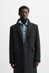 Abrigo negro regular fit confeccionado en paño con lana. Tiene cuello con solapas de muesca, manga larga, bolsillos de solapa en la cadera, bolsillo interior, abertura en el centro de la espalda y cierre frontal con botonadura.
