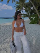 Pantalón blanco de tiro alto con corte palazzo y cordón ajustable en la cintura.