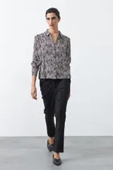 Camisa de manga larga color marrón con estampado de lunares blancos, confeccionada en tejido liviano con cuello clásico y botones frontales.