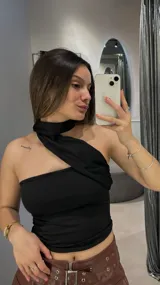 Top negro con diseño cruzado en el cuello y un hombro descubierto.