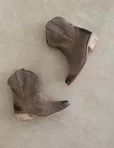 Botas cortas negras de cuero con bordados blancos estilo cowboy.