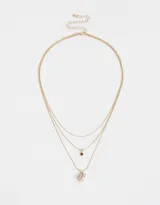 Collar dorado multicadena con dije de corazón rosa y dije de cristal rojo.