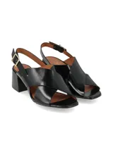 Sandalias negras de charol con tiras cruzadas, tacón cuadrado y pulsera al tobillo con hebilla metálica.