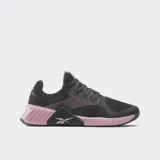 Championes de entrenamiento Reebok Flip Charge, color gris oscuro con detalles en rosado. Presentan una malla transpirable en la parte superior y una suela robusta con soporte lateral reforzado en color rosado y negro.