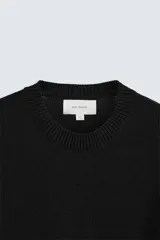 Jersey negro de corte boxy fit, tejido en hilatura con mezcla de algodón y 13% de cashmere. Tiene cuello redondo, manga larga y acabados en rib.