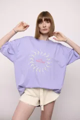 Remera lila de corte holgado con estampado de nadadoras en círculo.