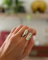 Anillo de diseño orgánico y macizo, realizado artesanalmente en bronce. Presenta una estructura abierta con dos piezas de forma irregular y textura rugosa.