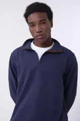 Buzo de friza gris con cuello alto y cierre parcial con cremallera.