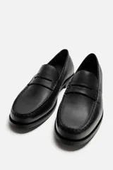 Mocasín de cuero negro con antifaz en el empeine y suela a tono con ligero tacón.