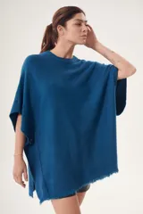 Poncho azul con cuello redondo y terminación desflecada.
