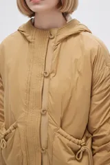 Campera negra de manga larga con capucha, cierre frontal con botones a presión, bolsillos laterales y cordón ajustable en la cintura.