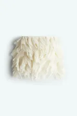 Minifalda color crudo de crepé de gasa con volados plisados y diseño calado. Tiene cierre oculto y cierre de corchete a un lado. Está forrada.