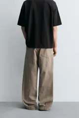 Pantalón de jean color marrón topo, de corte holgado y amplio en toda la pierna, con tiro medio, cinco bolsillos, efecto lavado, detalle de pinzas en perneras y cierre frontal con cremallera y botón.