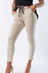 Pantalón color beige de corte Aline, con cintura plisada, bolsillos delanteros y lazo con estampado animal print.