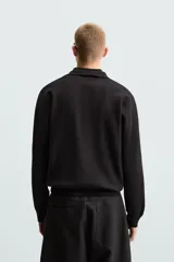 Polo de manga larga color negro, tejido en punto de algodón, corte relaxed fit, cuello solapa y cierre frontal con botonadura.