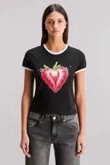 Remera blanca de calce slim, escote redondo y manga corta, con ribete negro en cuello y mangas. Estampa frontal de una frutilla roja con la frase "Bite Me".