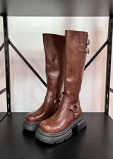 Botas de caña alta color marrón con doble hebilla y cierre en la parte trasera.