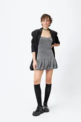 Vestido corto de lurex plateado y negro, sin mangas, con breteles finos regulables y volados tipo balloon desde la cadera.