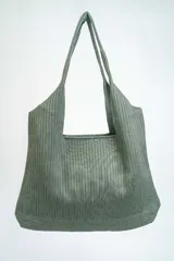 Bolso negro tipo tote bag con textura acanalada y asas de hombro.