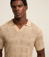 Remera polo de manga corta color beige, con cuello inglés y textura patchwork en cuadrados.