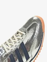 Zapatillas Adidas SL 72 plateadas con detalles en azul marino, suela de goma marrón y cordones blancos.