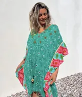 Túnica corta verde con estampado de flores rojas y detalles bordados. Mangas anchas con terminación en volados con estampado floral en tonos rosa y celeste.