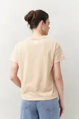 Remera blanca de manga corta con estampado de una concha marina y la frase "ocean breeze, mind at ease" en color marrón.