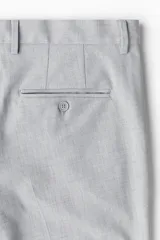 Pantalón de vestir gris claro, de corte slim fit, con pliegues frontales, bolsillos laterales y traseros ribeteados con botón.