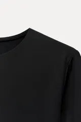 Body negro de poliamida con cuello redondo, corte ajustado y mangas largas. Cierre inferior con broches a presión.
