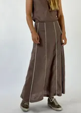 Conjunto de top con breteles finos y pollera larga marrón con líneas verticales blancas.