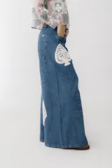 Pantalón de jean azul de corte wide leg con aplicaciones de crochet en forma de corazón, trébol, diamante y pica.