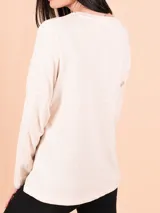 Remera beige de manga larga con la frase "One of a kind" estampada en el frente.