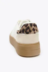 Zapatillas deportivas blancas con suela marrón en contraste y detalle de estampado animal en la parte trasera.