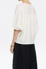 Camiseta blanca de manga corta con cuello redondo, corte holgado y apliques de pequeñas perlas en la parte delantera.