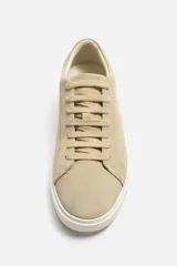 Zapatillas bajas color beige de gamuza, con cordones y suela blanca.