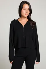 Campera negra de tejido de punto con ajuste holgado, cuello de banda, cierre frontal con cremallera y mangas cortadas al bies.