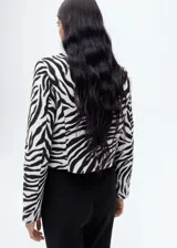Chaqueta con estampado de cebra, cuello de solapa, diseño recto, cierre delantero con botones, forro interior y dos bolsillos de solapa en la parte frontal.