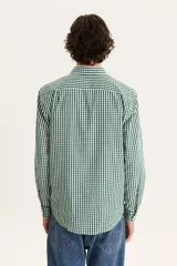 Camisa de manga larga a cuadros verdes y blancos, con cuello clásico, cierre con botones y bolsillo en el pecho.