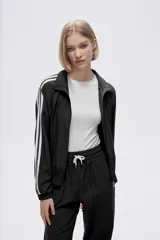 Campera deportiva verde con cierre frontal, cuello alto y tres rayas blancas en las mangas.