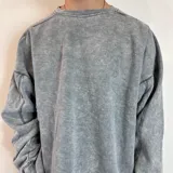 Buzo celeste con efecto gastado, corte amplio, cuello redondo y puños y cintura acanalados.